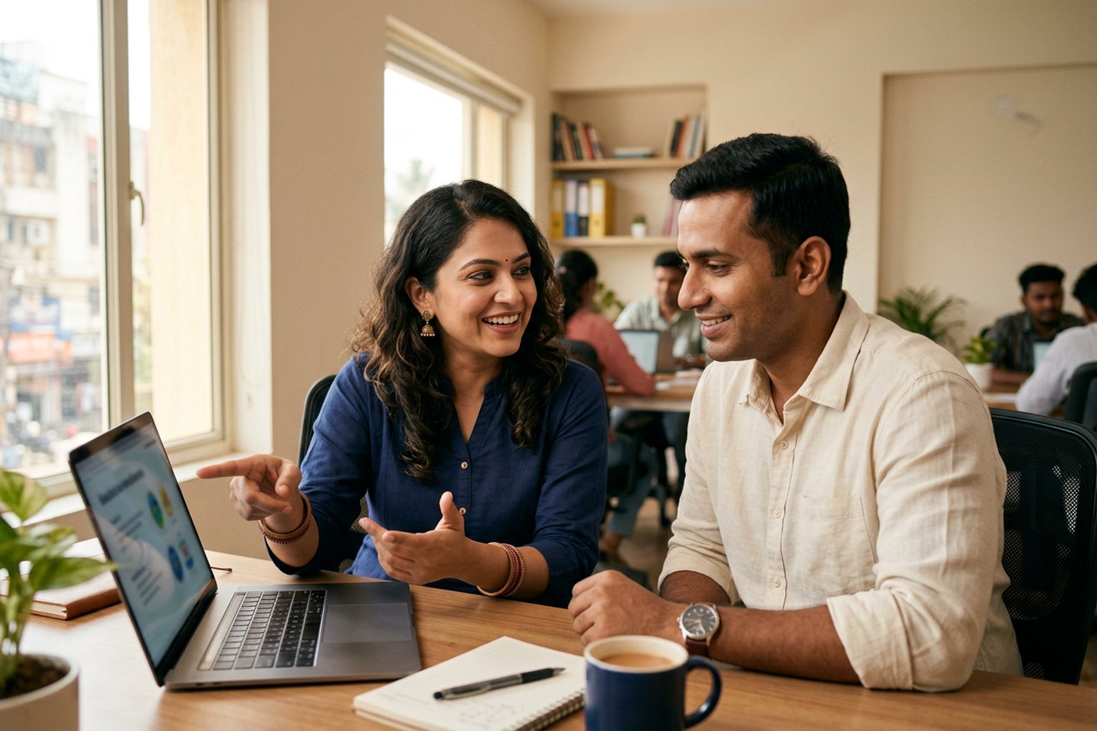 Two colleagues discussing course content over a laptop in an office in India